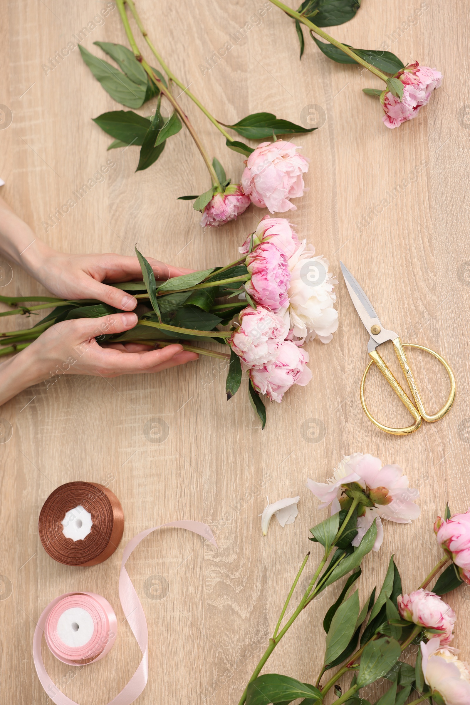 Florist making bouquet of flowers at wooden table, top view Photo of Florist making bouquet of flowers at wooden table, top view