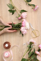 Photo of Florist making bouquet of flowers at wooden table, top view