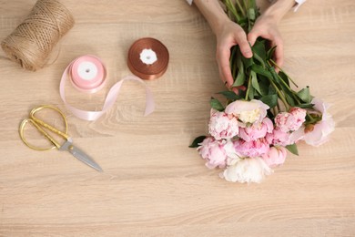 Photo of Florist making bouquet of flowers at wooden table, above view