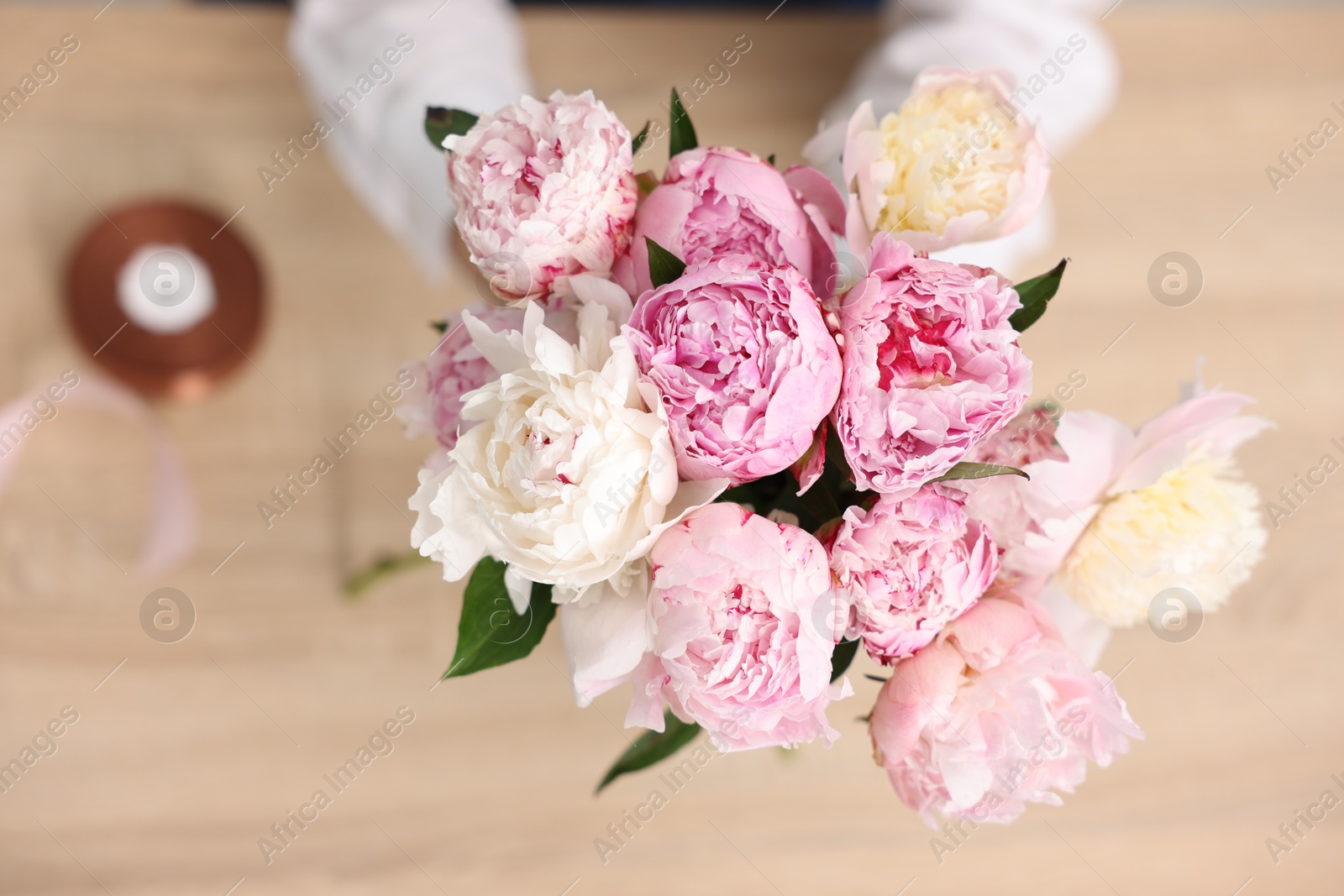 Florist with beautiful bouquet of peonies at table, top view Photo of Florist with beautiful bouquet of peonies at table, top view