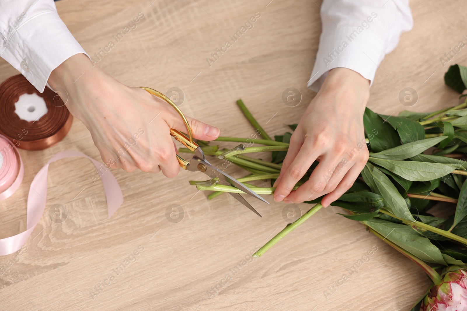 Florist making bouquet of flowers at wooden table, top view Photo of Florist making bouquet of flowers at wooden table, top view