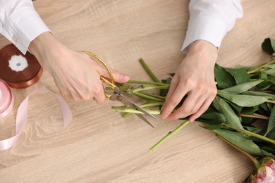 Photo of Florist making bouquet of flowers at wooden table, top view