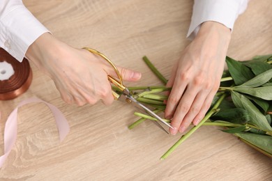 Photo of Florist making bouquet of flowers at wooden table, top view