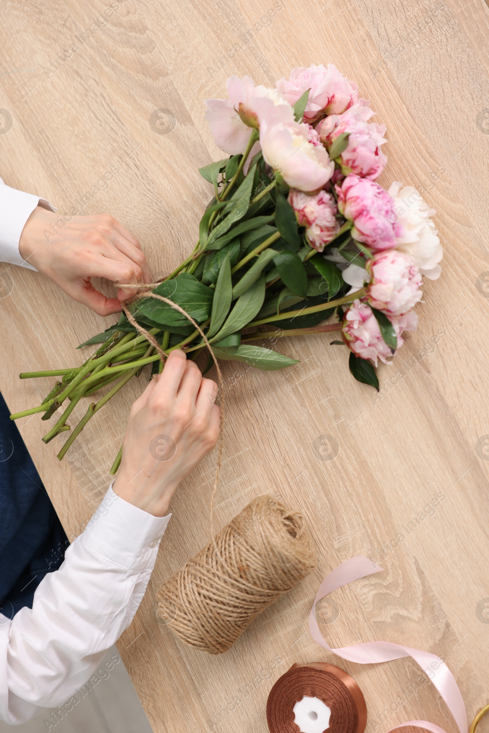 Florist making bouquet of flowers at wooden table, top view Photo of Florist making bouquet of flowers at wooden table, top view