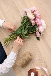 Photo of Florist making bouquet of flowers at wooden table, top view
