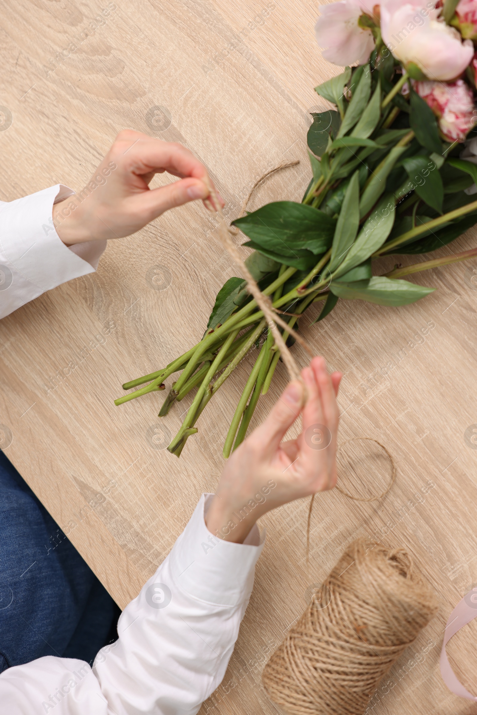 Florist making bouquet of peonies at wooden table, top view Photo of Florist making bouquet of peonies at wooden table, top view