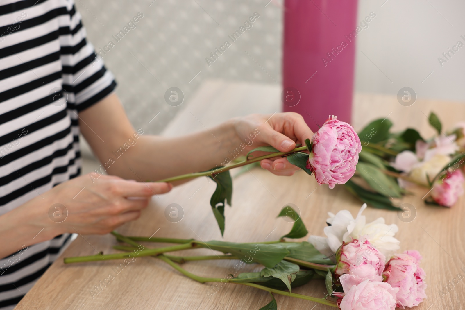 Florist making bouquet of peonies at wooden table in flower shop, closeup Photo of Florist making bouquet of peonies at wooden table in flower shop, closeup