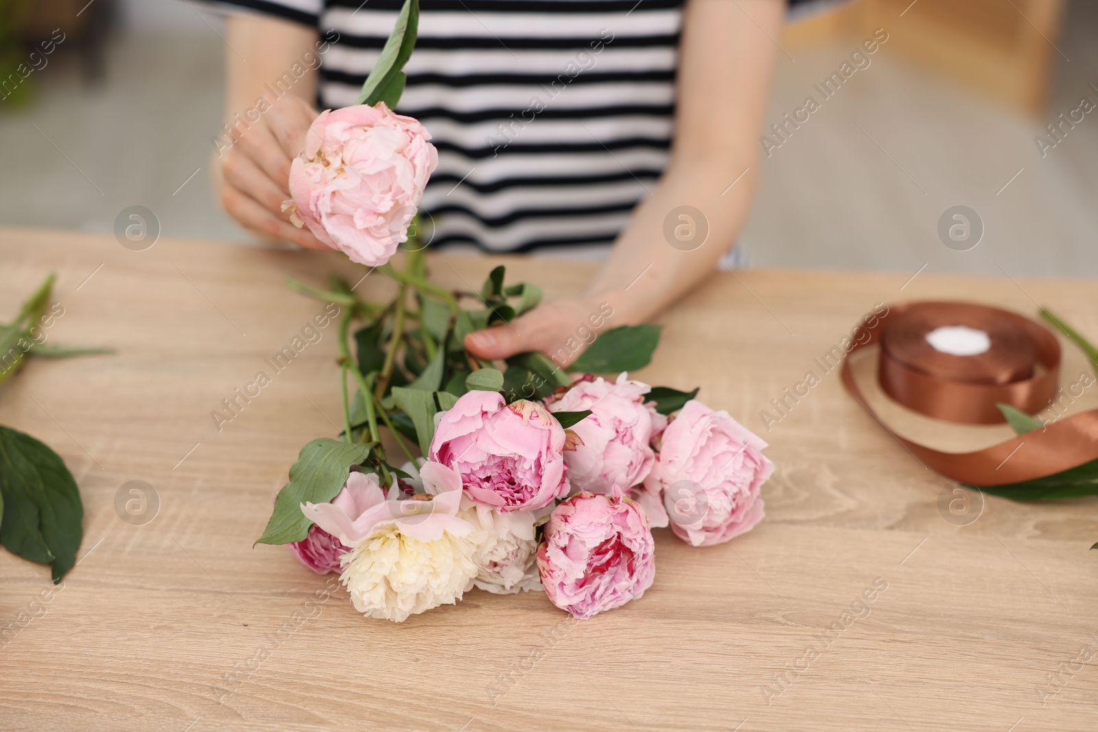 Florist making bouquet of peonies at wooden table in flower shop, closeup Photo of Florist making bouquet of peonies at wooden table in flower shop, closeup