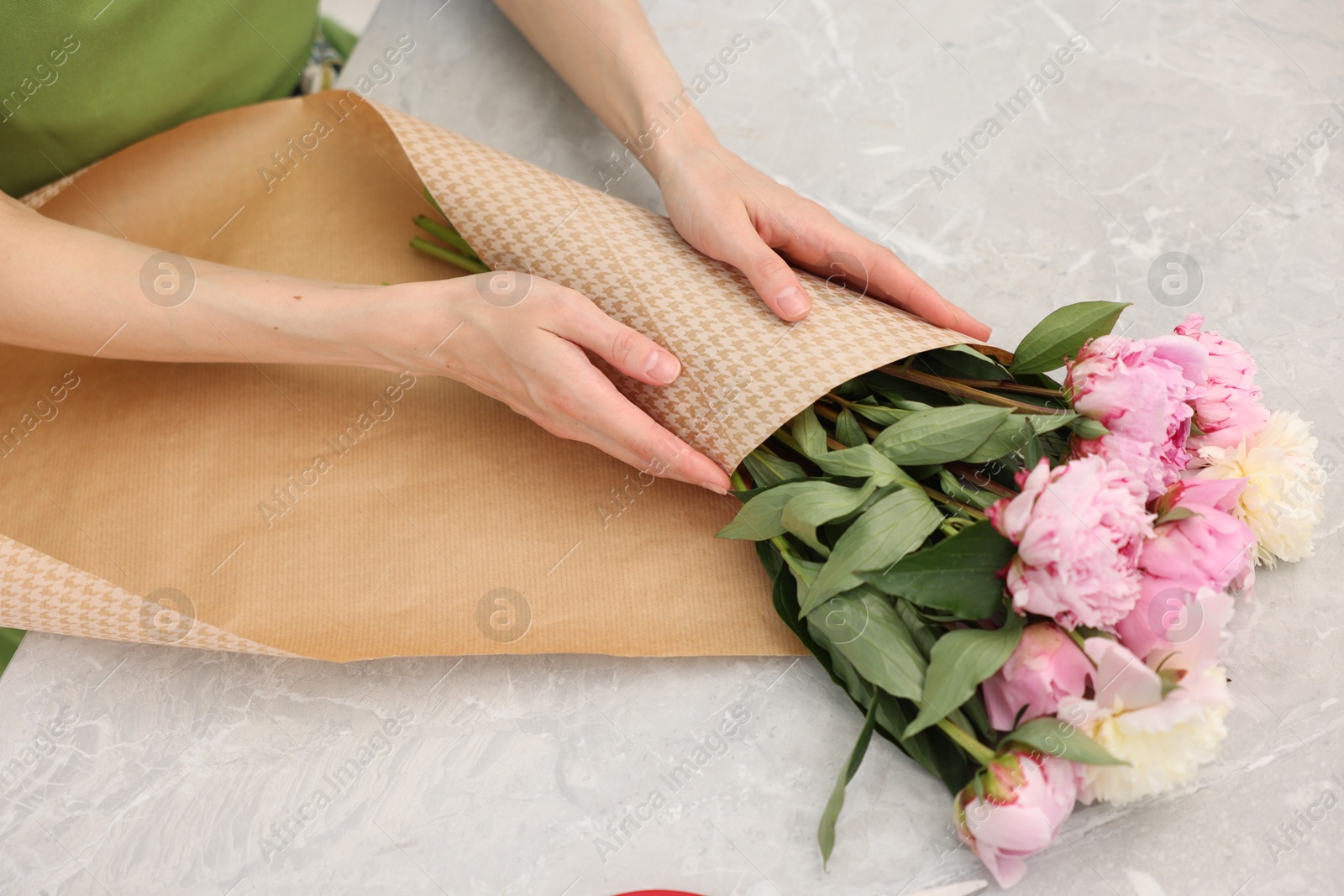 Florist making bouquet of peonies at grey marble table, above view Photo of Florist making bouquet of peonies at grey marble table, above view
