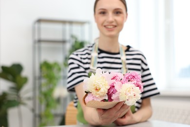 Photo of Florist with bouquet of peonies in flower shop, selective focus. Space for text