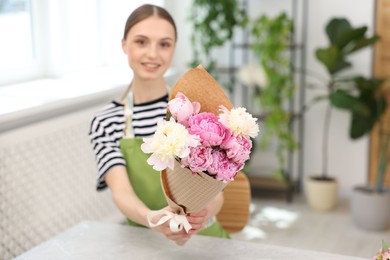 Photo of Florist with beautiful bouquet of peonies in flower shop, selective focus