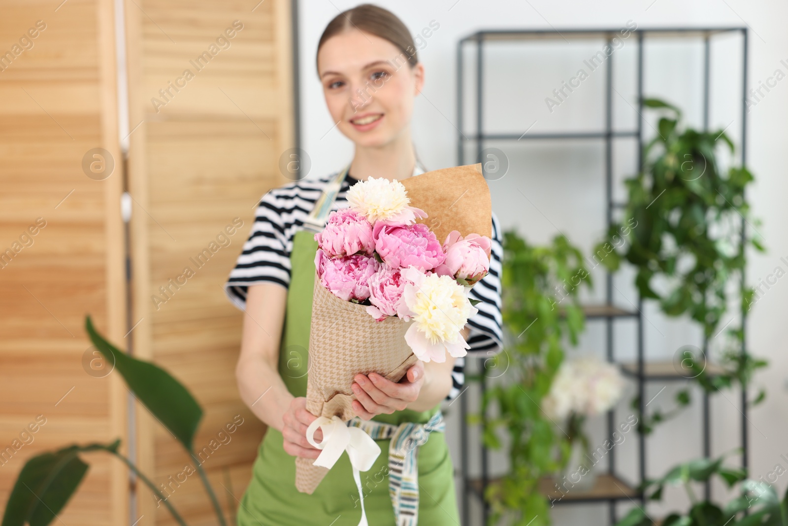 Florist with beautiful bouquet of peonies in flower shop, selective focus Photo of Florist with beautiful bouquet of peonies in flower shop, selective focus