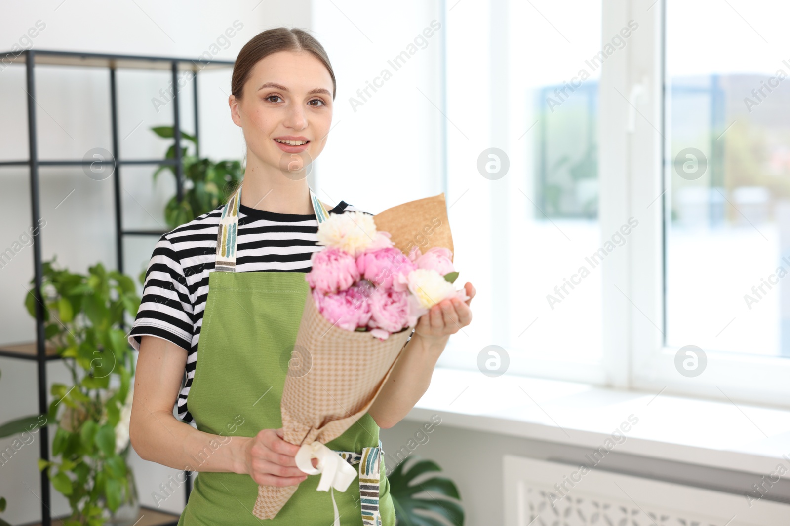 Florist with beautiful bouquet of peonies in flower shop, space for text Photo of Florist with beautiful bouquet of peonies in flower shop, space for text