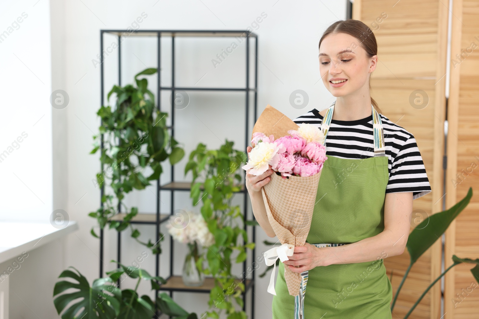 Florist with beautiful bouquet of peonies in flower shop, space for text Photo of Florist with beautiful bouquet of peonies in flower shop, space for text