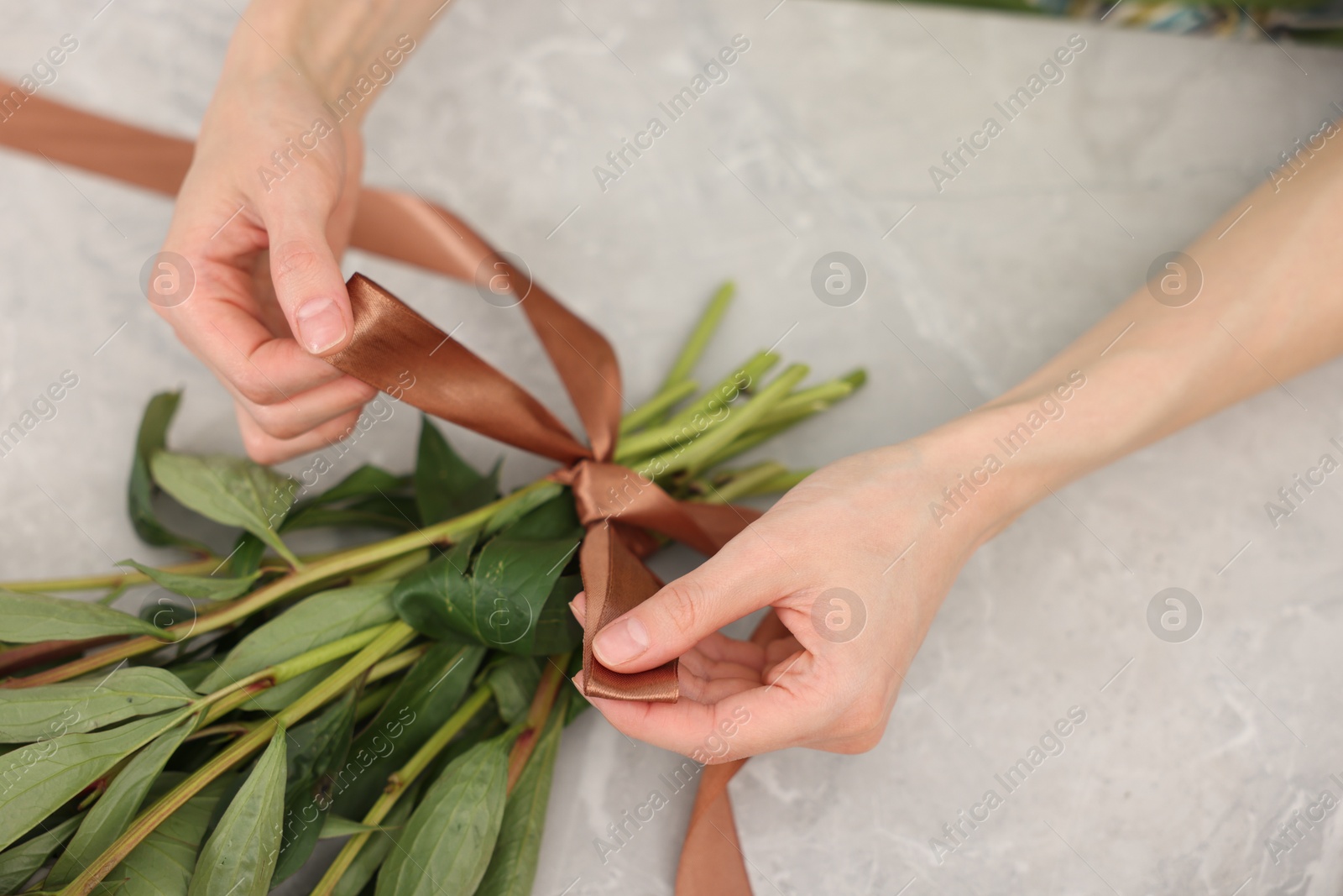 Florist making beautiful bouquet of flowers at grey marble table, top view Photo of Florist making beautiful bouquet of flowers at grey marble table, top view