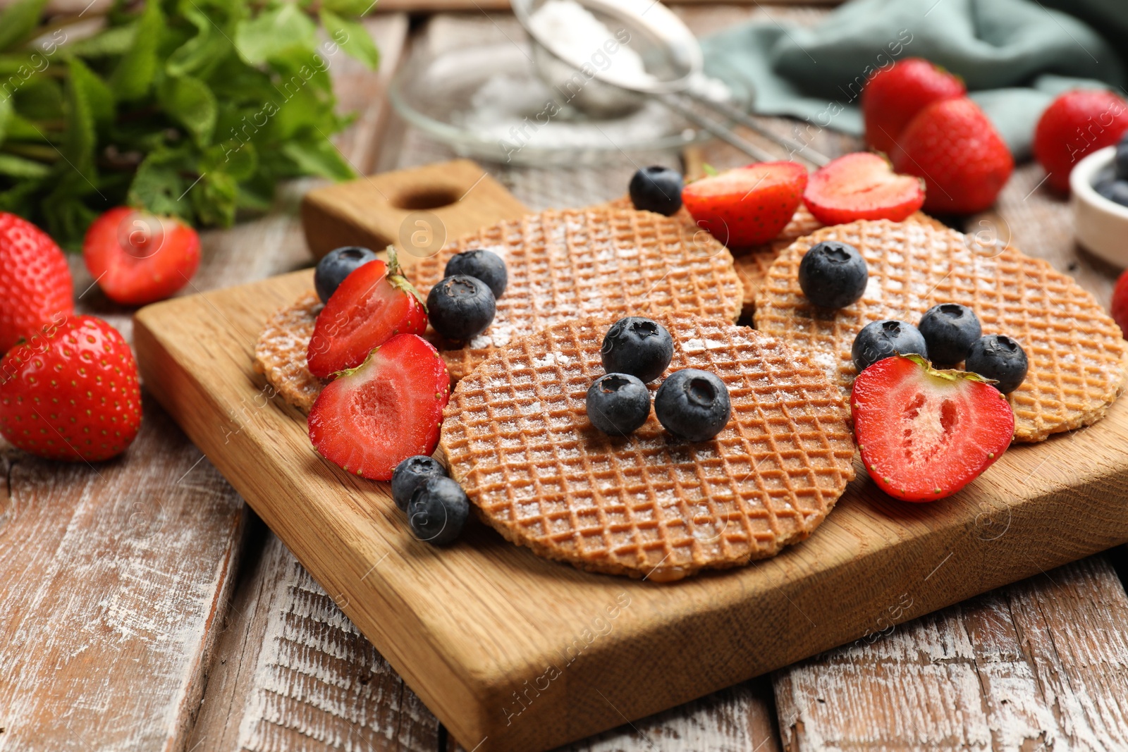 Tasty Dutch waffles (stroopwafels) and berries on wooden table, closeup Photo of Tasty Dutch waffles (stroopwafels) and berries on wooden table, closeup