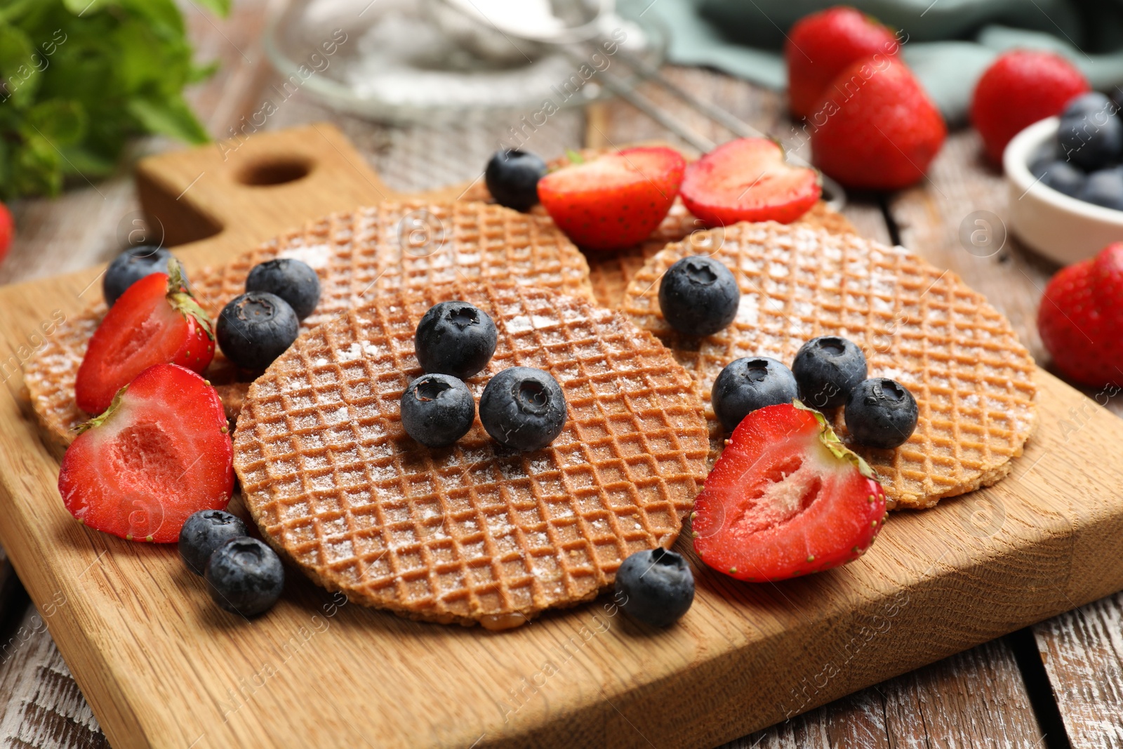 Tasty Dutch waffles (stroopwafels) and berries on wooden table, closeup Photo of Tasty Dutch waffles (stroopwafels) and berries on wooden table, closeup