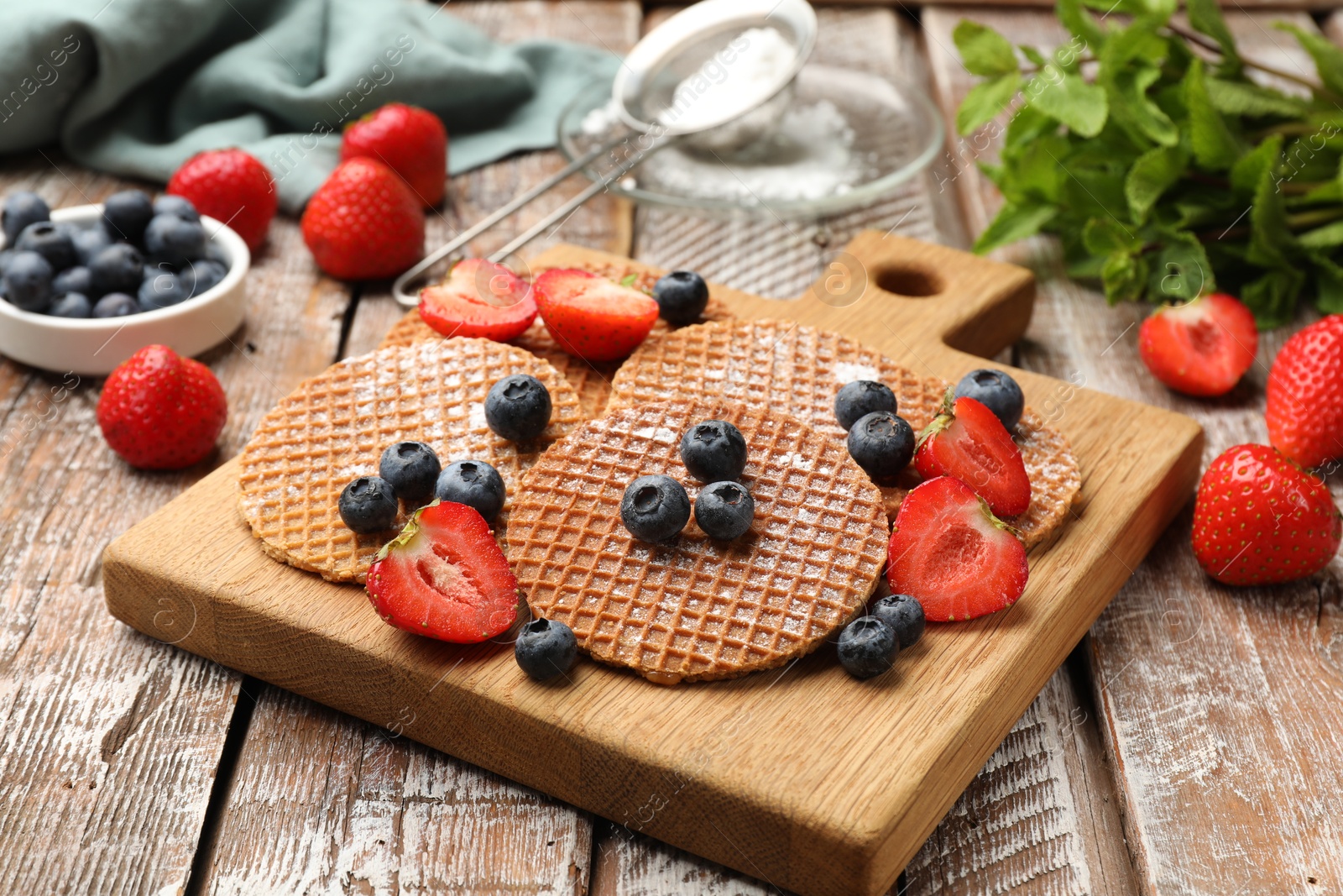 Tasty Dutch waffles (stroopwafels) and berries on wooden table, closeup Photo of Tasty Dutch waffles (stroopwafels) and berries on wooden table, closeup