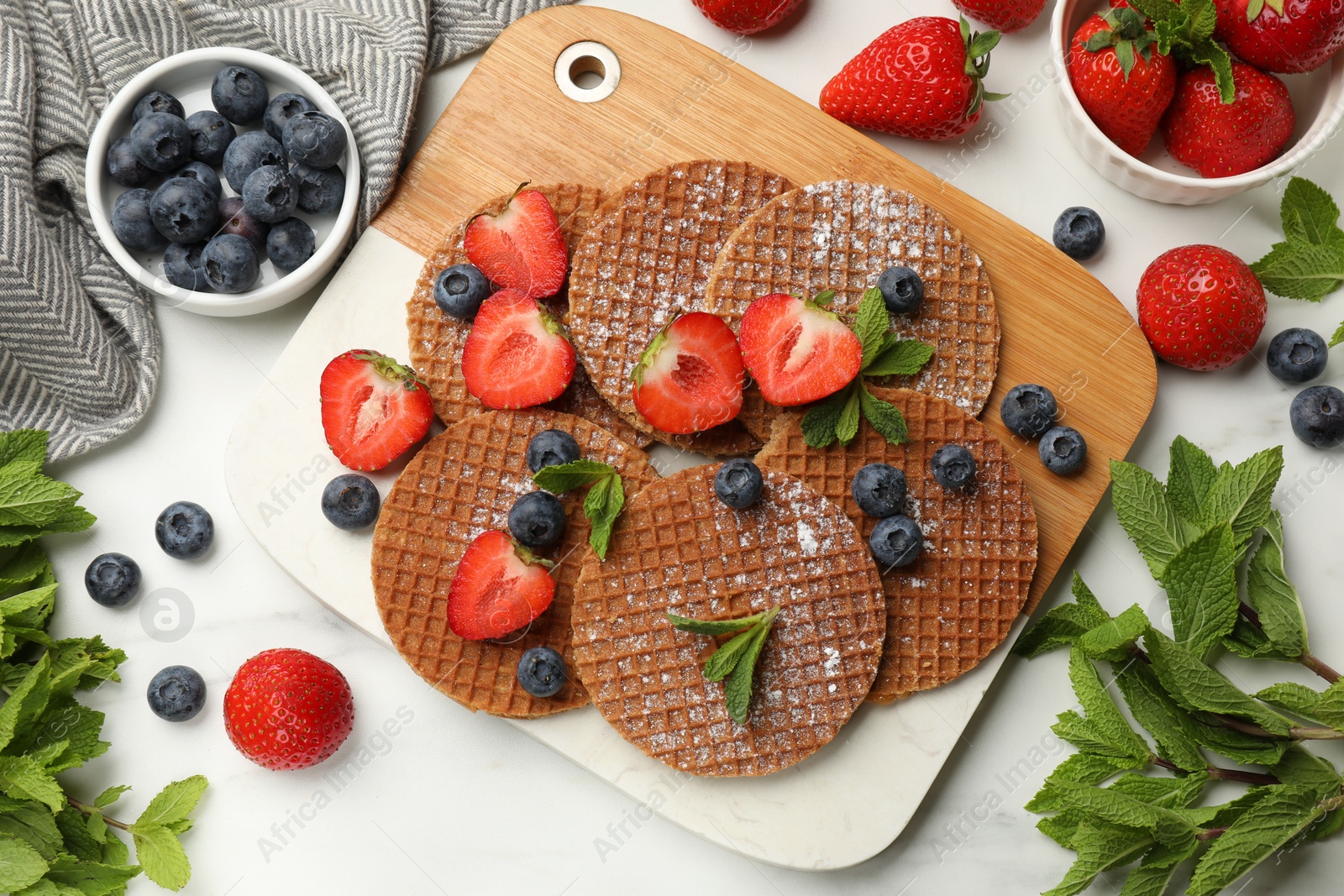 Tasty Dutch waffles (stroopwafels), mint and berries on white marble table, flat lay Photo of Tasty Dutch waffles (stroopwafels), mint and berries on white marble table, flat lay