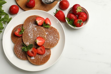Photo of Tasty Dutch waffles (stroopwafels), mint and strawberries on white marble table, flat lay. Space for text