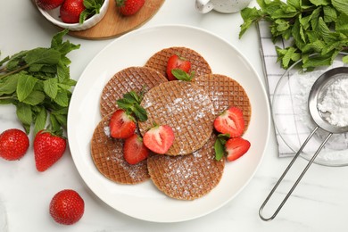 Photo of Tasty Dutch waffles (stroopwafels), mint and strawberries on white marble table, flat lay