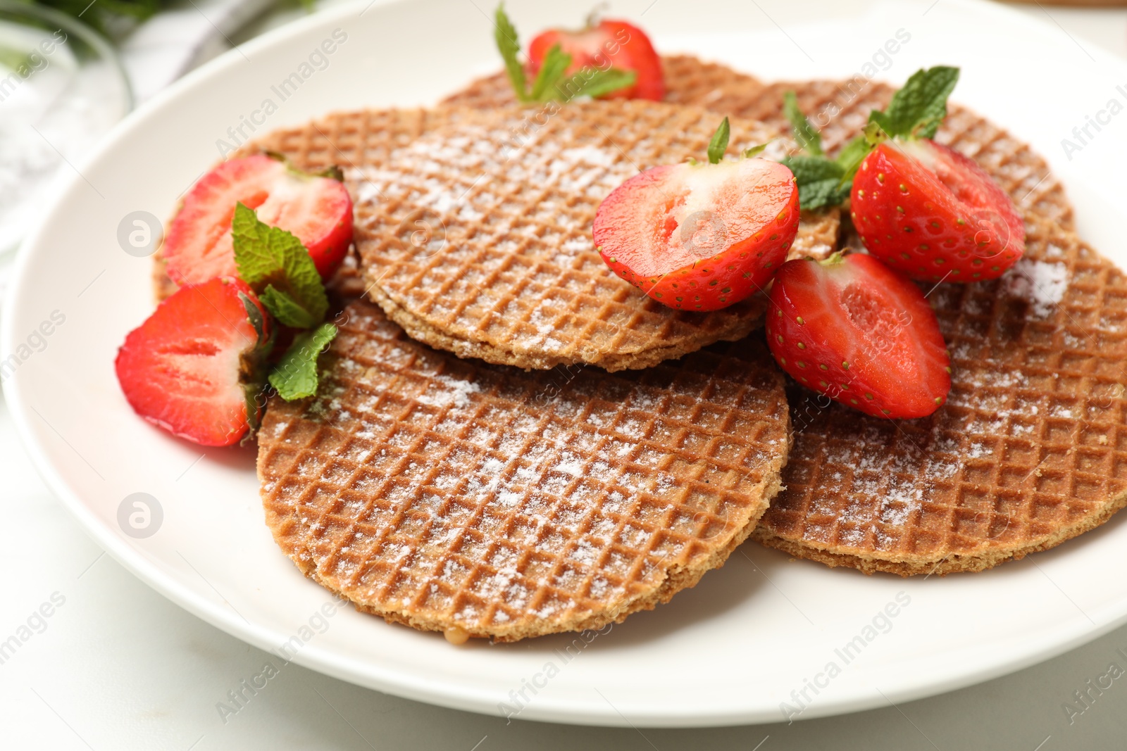 Tasty Dutch waffles (stroopwafels), mint and strawberries on white marble table, closeup Photo of Tasty Dutch waffles (stroopwafels), mint and strawberries on white marble table, closeup