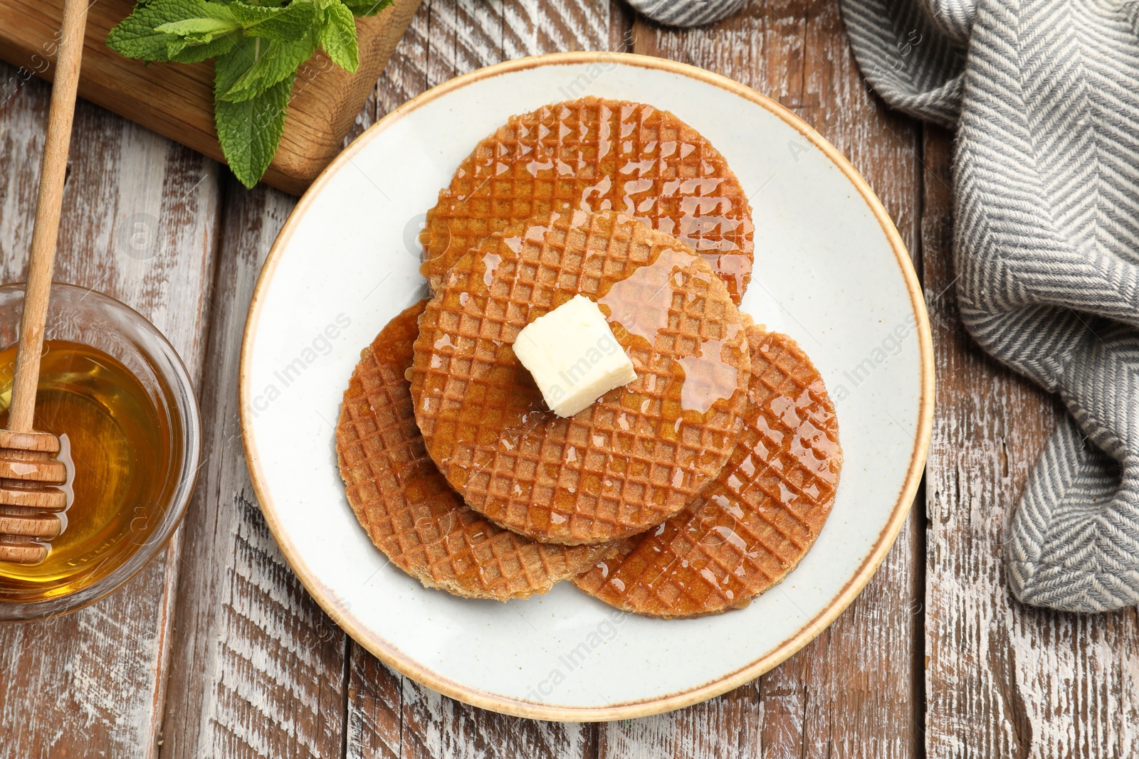 Tasty Dutch waffles (stroopwafels) with honey and butter cube on wooden table, flat lay Photo of Tasty Dutch waffles (stroopwafels) with honey and butter cube on wooden table, flat lay