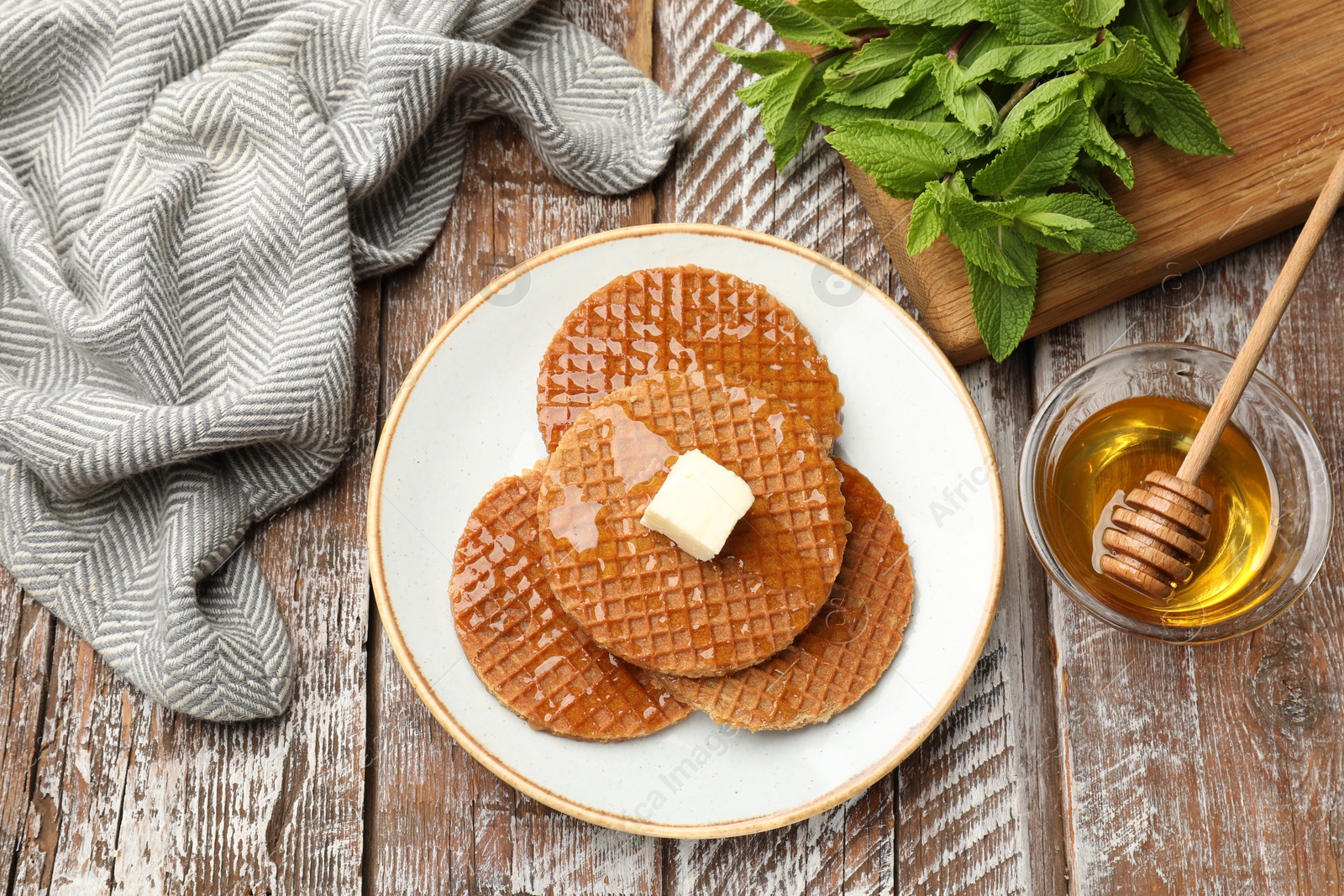 Tasty Dutch waffles (stroopwafels) with honey and butter cube on wooden table, flat lay Photo of Tasty Dutch waffles (stroopwafels) with honey and butter cube on wooden table, flat lay