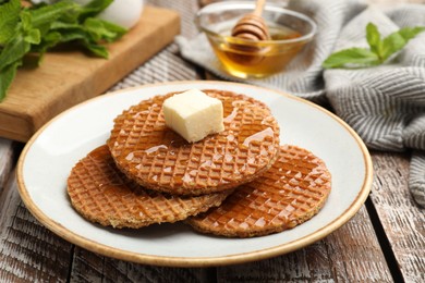 Photo of Tasty Dutch waffles (stroopwafels) with honey and butter cube on wooden table, closeup