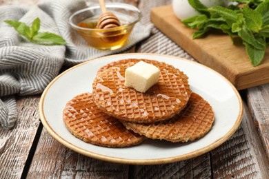 Photo of Tasty Dutch waffles (stroopwafels) with honey and butter cube on wooden table, closeup