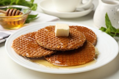 Photo of Tasty Dutch waffles (stroopwafels) with honey and butter cube on white table, closeup