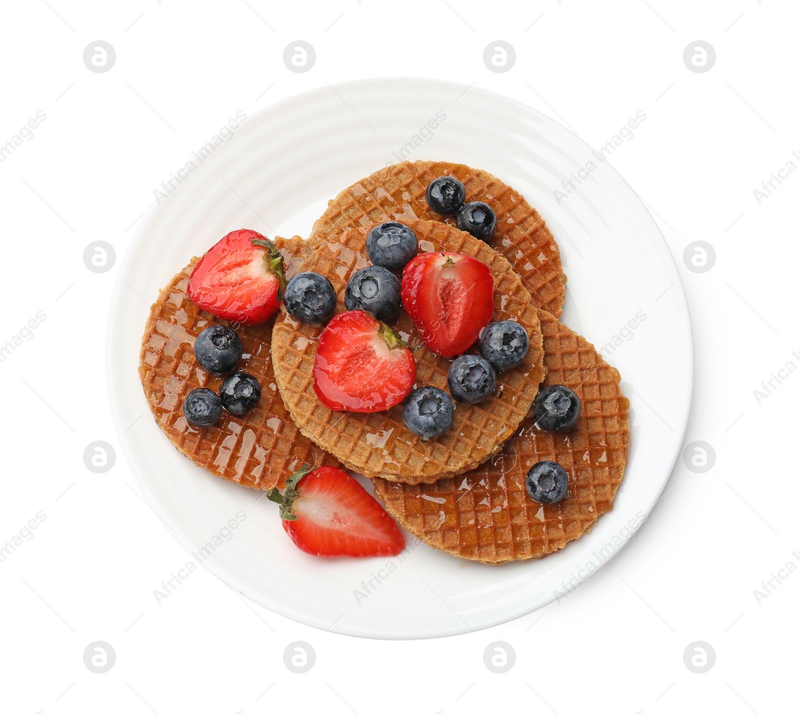 Tasty Dutch waffles (stroopwafels) with honey, strawberries and blueberries isolated on white, top view Photo of Tasty Dutch waffles (stroopwafels) with honey, strawberries and blueberries isolated on white, top view