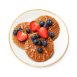 Photo of Tasty Dutch waffles (stroopwafels) with honey, strawberries and blueberries isolated on white, top view