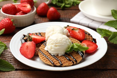 Photo of Tasty Dutch waffles (stroopwafels) with strawberries, ice cream and chocolate sauce on wooden table, closeup