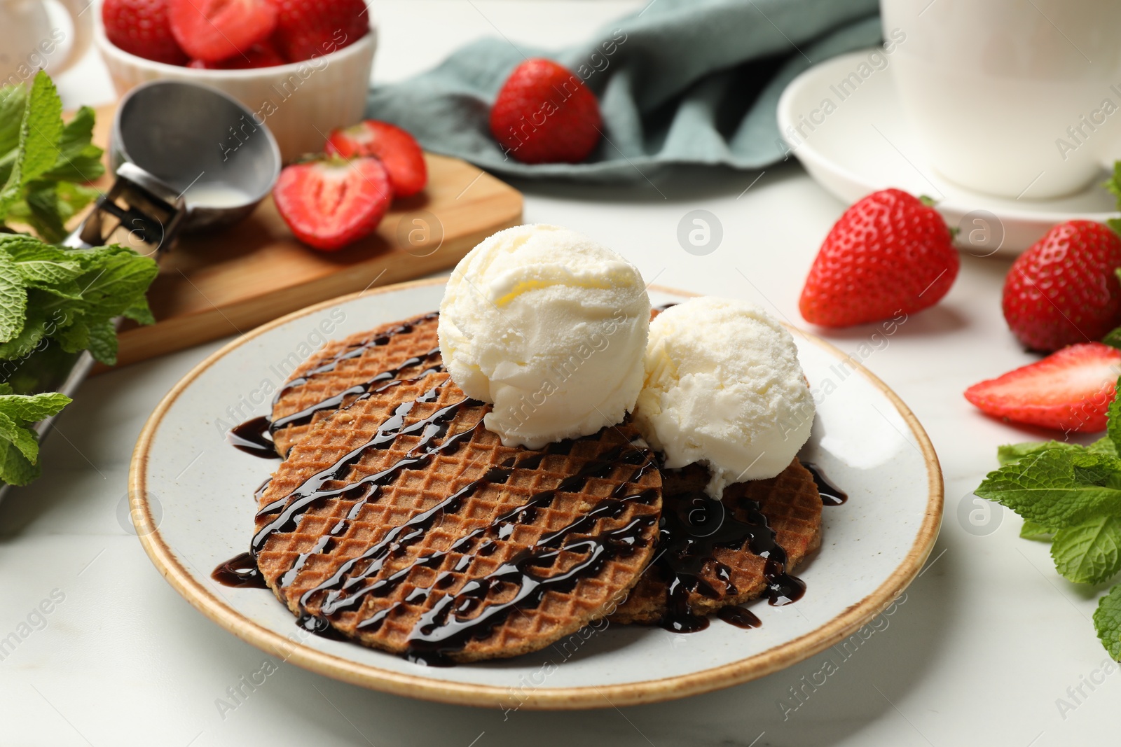 Tasty Dutch waffles (stroopwafels) with ice cream and chocolate sauce on white table, closeup Photo of Tasty Dutch waffles (stroopwafels) with ice cream and chocolate sauce on white table, closeup