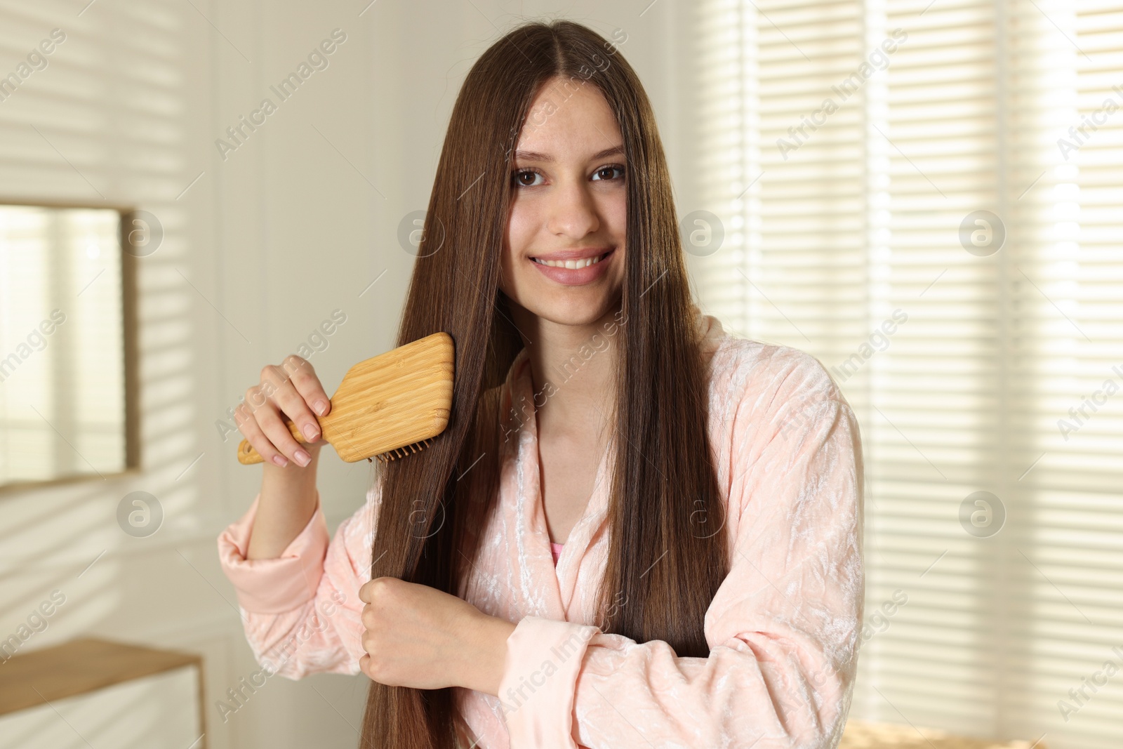 Smiling teenage girl brushing her shiny hair at home Photo of Smiling teenage girl brushing her shiny hair at home