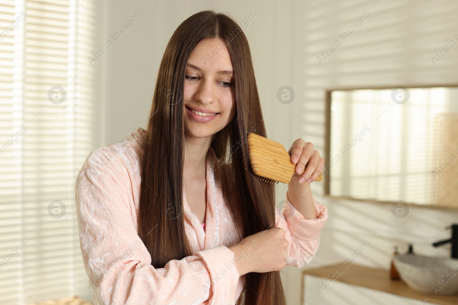 Smiling teenage girl brushing her shiny hair at home Photo of Smiling teenage girl brushing her shiny hair at home