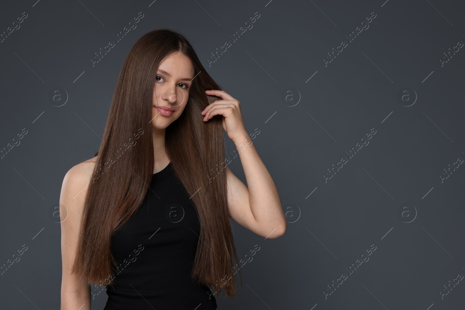 Portrait of beautiful teenage girl with healthy long hair on dark grey background. Space for text Photo of Portrait of beautiful teenage girl with healthy long hair on dark grey background. Space for text