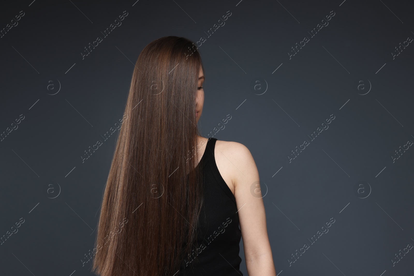 Teenage girl with healthy long hair on dark grey background. Space for text Photo of Teenage girl with healthy long hair on dark grey background. Space for text