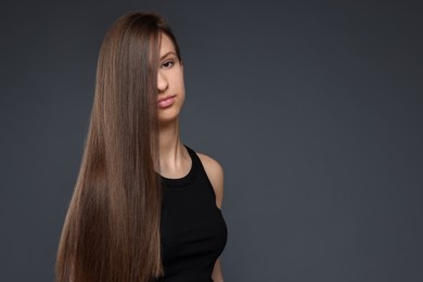 Photo of Teenage girl with healthy long hair on dark grey background. Space for text