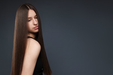 Photo of Beautiful teenage girl with healthy long hair on dark grey background. Space for text