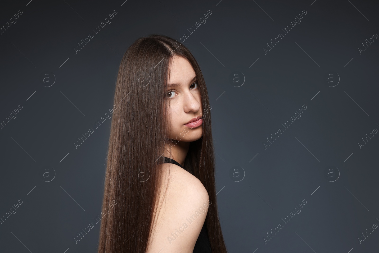 Beautiful teenage girl with healthy long hair on dark grey background. Space for text Photo of Beautiful teenage girl with healthy long hair on dark grey background. Space for text