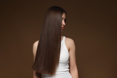 Photo of Teenage girl with healthy long hair on brown background