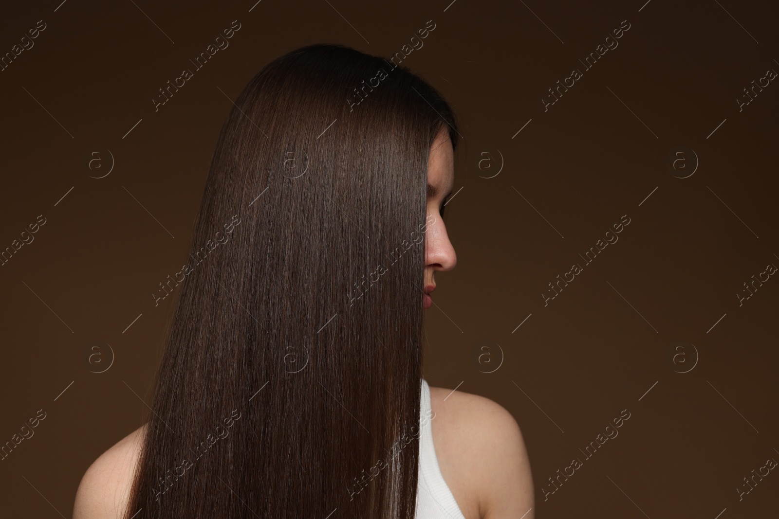 Teenage girl with healthy long hair on brown background Photo of Teenage girl with healthy long hair on brown background
