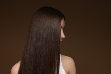 Photo of Teenage girl with healthy long hair on brown background