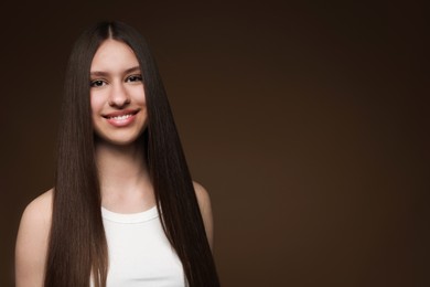 Photo of Portrait of smiling teenage girl with healthy long hair on brown background. Space for text