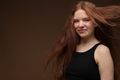 Photo of Portrait of beautiful teenage girl with healthy wavy hair on brown background. Space for text