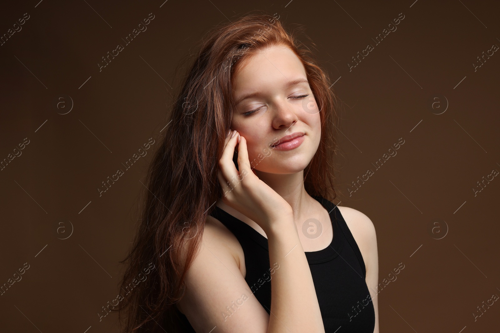 Beautiful teenage girl with healthy wavy hair on brown background Photo of Beautiful teenage girl with healthy wavy hair on brown background
