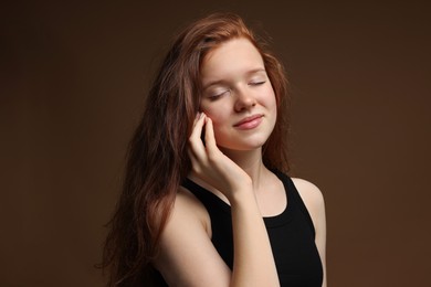 Photo of Beautiful teenage girl with healthy wavy hair on brown background