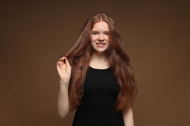 Photo of Portrait of smiling teenage girl with healthy wavy hair on brown background